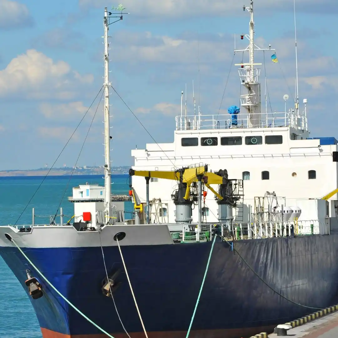 A large dark-hulled ore carrier moored at a deep-water pier