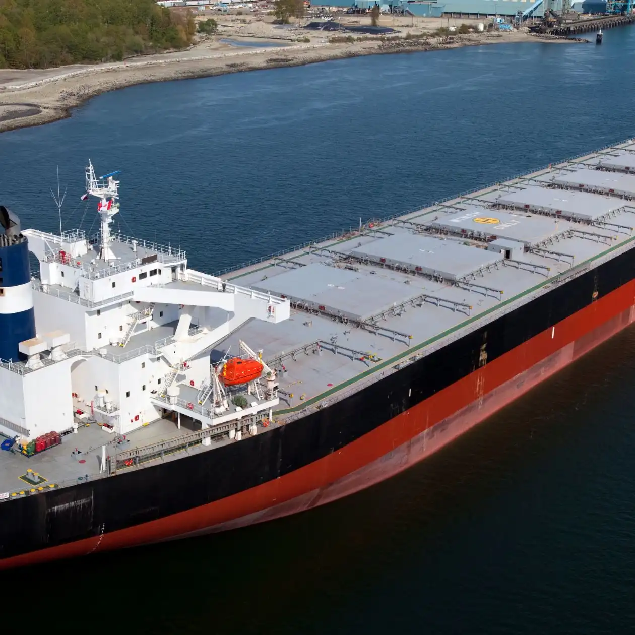 A laden bulk carrier with flat hatch covers underway near land